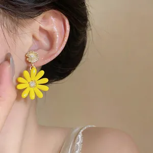 Detail shot of bright yellow daisy drop earrings worn on ear with crystal center