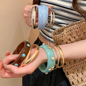 Close-up detail of resin bangle set with starfish and pearl accents on model's wrist