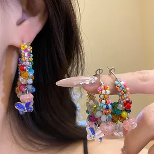 Close-up of colorful crystal beaded hoop earrings with butterfly and flower charms.