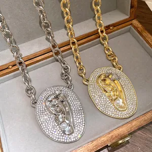 Macro detail view of luxury zircon pavé oval ear pendant necklace with pearl accent