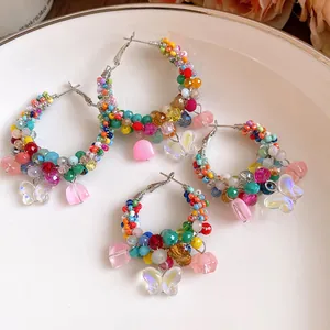 Detail showing colorful crystal beaded hoop earrings with iridescent butterfly charms