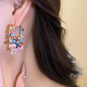 Detailed shot of multi-color crystal beaded hoop earring with a butterfly charm