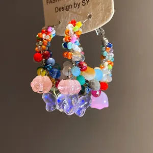 Detailed macro shot of colorful crystal beaded hoop earrings with butterfly charms