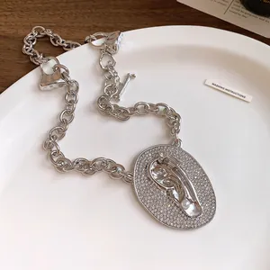 Close-up of fashion silver chain necklace with zircon-encrusted ear pendant and pearl