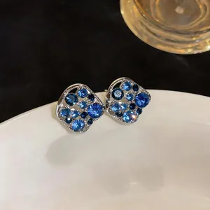 Close-up of elegant hollow square stud earrings with sparkling blue rhinestones