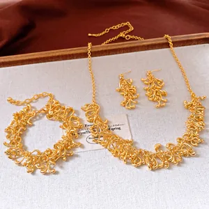 Détail d'une parure de bijoux dorés avec des motifs de glands géométriques irréguliers