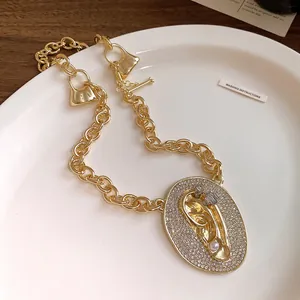 Macro view of gold chunky chain necklace featuring pavé zircon ear pendant and pearl detail