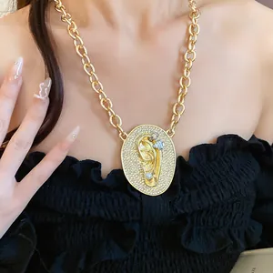 Detailed view of gold chain necklace with zirconia encrusted ear-shaped oval pendant