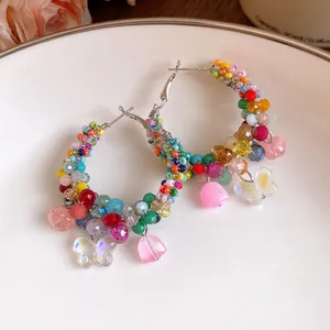 Detailed view of colorful crystal beaded hoop earrings with butterfly and flower charms