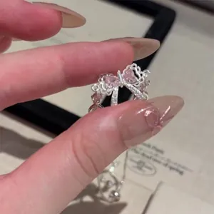 Detailed close-up of a silver bow ring featuring pink heart-shaped stones and clear accents.