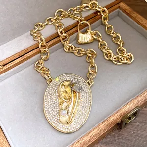 Close-up of gold ear pendant necklace with zircon and pearl details in velvet box
