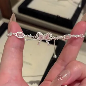 Macro shot of silver-colored bracelet featuring a delicate pink zircon bow pendant