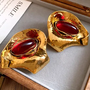 Primo piano di orecchini vintage dorati martellati con resina rossa ovale