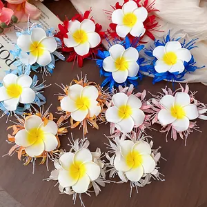 Detailansicht bunter Plumeria-Stoffblumen-Haarspangen auf einem Holztisch angeordnet.