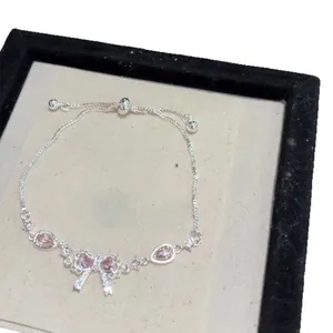 Elegant silver-toned bow bracelet with sparkling pink zircon stones and adjustable chain.