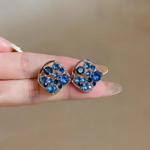 Macro detail of elegant hollow square stud earrings featuring sparkling blue rhinestones