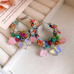Detail of handmade beaded hoop earrings with crystal butterfly and flower charms