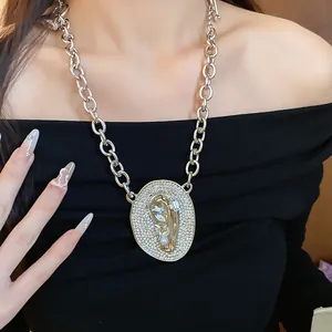 Close-up of a silver chunky chain necklace with a crystal-encrusted oval ear pendant.