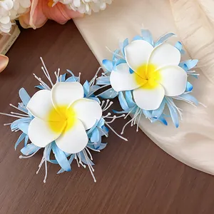 Detailansicht von zwei eleganten weiß-gelben Plumeria-Blüten-Haarspangen für Damen.