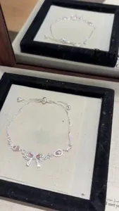 Detail of silver bow bracelet with pink zircons and adjustable sliding clasp.