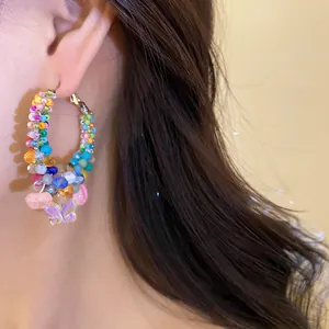 Close-up detail of colorful handmade crystal beaded hoop earrings with butterfly charms
