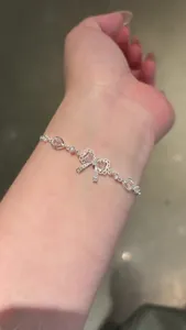 Close-up view of elegant silver bracelet with pink zircon bow-knot on wrist