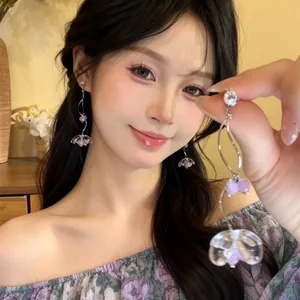 Close-up of purple floral tassel earrings with elegant wavy silver wire and sparkling zircon