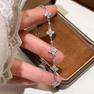 Elegant silver-toned bracelet featuring zircon flower motifs and turquoise accents on hand