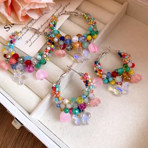 Close-up of colorful crystal beaded hoop earrings with butterfly and flower charms