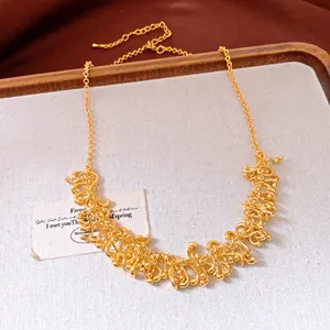 Vue détaillée d'un collier doré à franges métalliques irrégulières sur fond blanc.