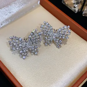 Nahaufnahme eleganter Zirkon-Schmetterlingsohrringe mit Perlenakzenten in einer Box