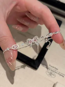 Detailed view of silver-tone bow bracelet with pink zircons and delicate chain.