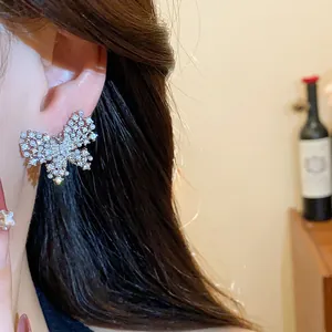 Detailaufnahme von eleganten Schmetterlingsohrsteckern mit Zirkonia und Perlen am Ohr