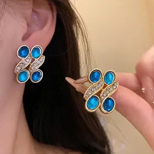 Elegant vintage gold-tone earrings featuring blue resin ovals and sparkling rhinestone accents.