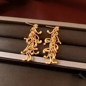 Vue détaillée de boucles d'oreilles pendantes en métal liquide doré au design géométrique