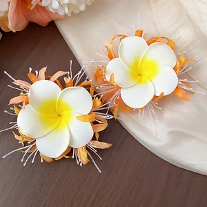 Detailansicht von tropischen Frangipani-Blüten-Haarspangen mit gelber Mitte und Orangerand.