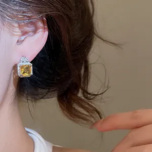 Detail view of a luxury square yellow zircon earring worn by a model for banquet styling