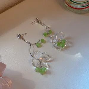 Close-up detail of exquisite green flower tassel earrings with clear acrylic petals and silver studs
