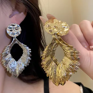 Detailed view of hammered metallic leaf statement earrings in gold and silver finish