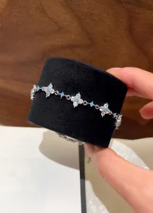 Detailed view of elegant silver-tone clover bracelet with clear zircons and blue gemstones