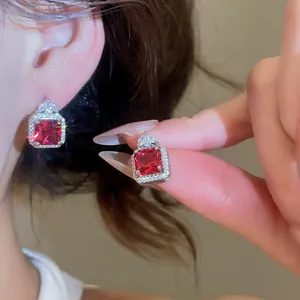 Close-up of elegant square red zircon earrings with shimmering halo design