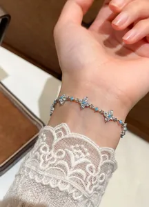 Detailed view of elegant silver zircon flower bracelet worn on wrist with lace sleeve