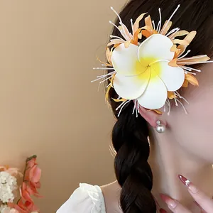 Detailaufnahme einer tropischen Plumeria-Blüten-Haarspange im geflochtenen Haar des Models.