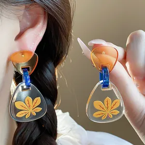 Primer plano detallado de pendientes triangulares de acetato con estampado de hoja de arce