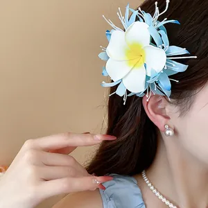 Detailansicht einer eleganten blau-weißen Plumeria-Stoffblumen-Haarklammer an einem Model.