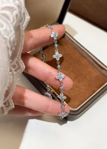 Close-up of elegant silver flower bracelet with sparkling zirconia and blue beads on hand