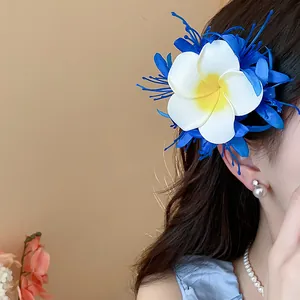 Nahaufnahme einer eleganten blau-weißen Plumeria-Blüten-Haarspange im Haar einer Frau