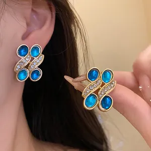 Detailed view of vintage gold-tone earrings with blue resin ovals and rhinestones