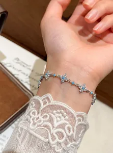 Close-up of a refined silver-tone zircon flower bracelet with turquoise beads on a wrist
