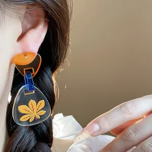 Vista detallada de los pendientes geométricos de acetato con estampado de hoja de arce amarilla